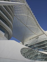Close-up of a modern building with a striking glass structure and a clear blue sky, dubai, arab