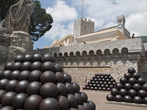 Historic fortress walls with cannonballs and a statue, under a slightly cloudy sky, Monte Carlo,