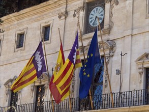 Historic building with four flags and a clock on the facade, palma de Majorca with its historic