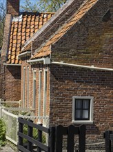Traditional brick houses with tiled roofs and fences glow in the sun, Enkhuizen, Nirderlande