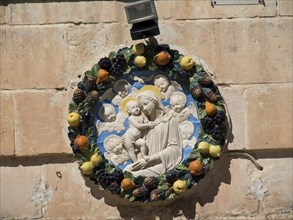 Round, colourful relief of religious art with the Virgin Mary and Child surrounded by fruit,