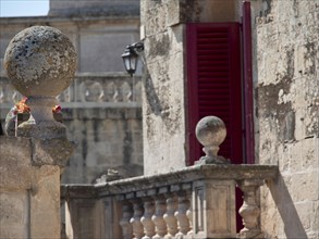 Close-up of historic architecture with stone balustrade and red shutters, the town of mdina on the