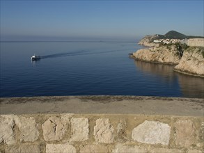 View of a rocky coastline with clear blue sea and peaceful horizon, the old town of Dubrovnik with