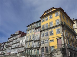 Facades of multi-storey colonial-style houses with yellow and white fronts under a blue sky,