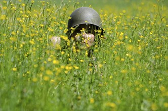 Scary Woman with Military Helmet Hidden in the Field with Yellow Flowers in a Sunny Day in