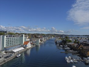 Urban view of a canal with boats and modern hotels on a sunny day, harbour in norway with boats,