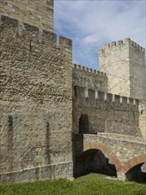 A medieval castle with high stone walls and a gate leading over a stone bridge, Lisbon, Portugal,