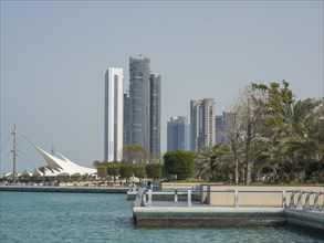 A coastline with modern high-rise buildings and a promenade that runs along the waterfront, Abu