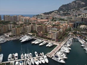 Harbour with many yachts, surrounded by buildings along the coast, under a clear sky in summer,