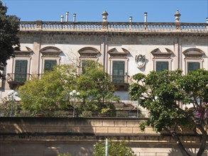 Historic building with green shutters and garden in a sunny setting, palermo in sicily with an