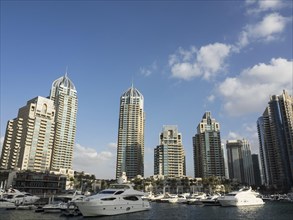 Harbour with yachts and modern skyscrapers in the background, partly cloudy sky, Dubai, Arab