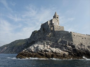 Historic church on a rocky coastal promontory, surrounded by sea and clear skies, Bari, Italy,