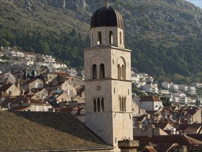 Historic church tower and city building with mountain backdrop, the old town of Dubrovnik with