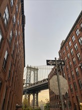 Bridge framed by tall red brick buildings with clearly visible street signs, new york from above