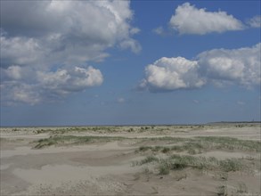 Open coastal landscape with sandy beach and a sky full of clouds over the sea, Baltrum Germany