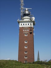 High brick lighthouse under blue sky with technical superstructures, Heligoland, Germany, Europe