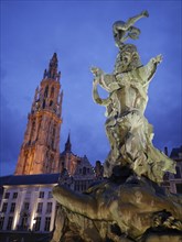 Detailed statue in front of an illuminated church tower and historic buildings, the historic market