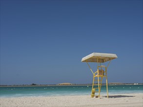 Abandoned lifeguard tower on a deserted beach with blue sky and calm sea, Abu Dhabi, Arab Emirates