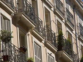 An apartment block with numerous balconies and shutters, partly decorated with plants, palma de