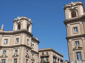 Two historic towers with beige facades under a clear sky, witnesses of classical architecture,