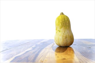 Pumpkin on a wooden table with a white wall in the background