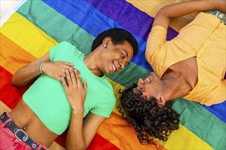 Top view of male latin gay couple lying on rainbow LGBT flag