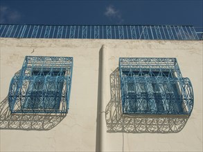 Decorative blue balconies on a white wall cast shadows, Tunis in Africa with ruins from Roman
