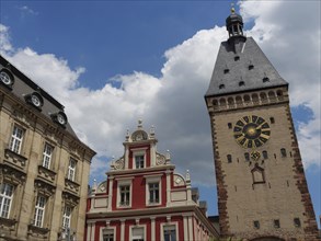 A clock tower and decorated building under a cloudy sky, tower with tower clock in front of