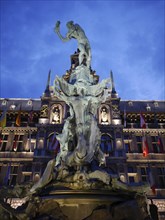 Statue on a fountain in front of an illuminated historical building at night, baroque architecture