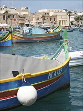 A traditionally painted fishing boat moored with other boats in a quiet harbour, colourful boats in
