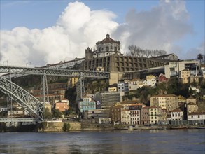 View of a monastery on a hill on the riverside with a bridge and colourful buildings in the