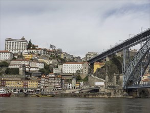 City view with colourful buildings on a hill, a bridge and a river in the foreground, Colourful