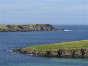 View of the blue sea with rocky cliffs and green grass in the foreground in calm weather, Green
