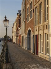 Narrow alley with cobblestones and historic houses in the warm evening light, Maastricht,