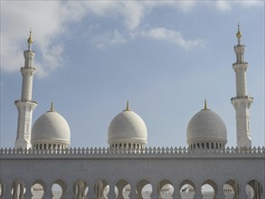 An impressive mosque with several minarets and golden domes under a blue sky, Abu Dhabi, United