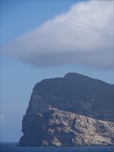 A large rock rising from the sea with clouds in the sky, palma de mallorca on the mediterranean sea