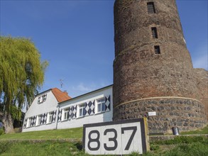 A stone tower and a house with the number 837 under a blue sky on a summer morning, rhine promenade