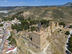 Historic castle complex on a hill in a mountainous area of Spain, surrounded by vegetation in sunny