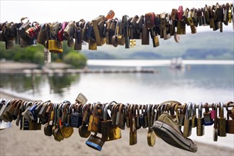 Many love locks on a railing with a lake and mountains in the background