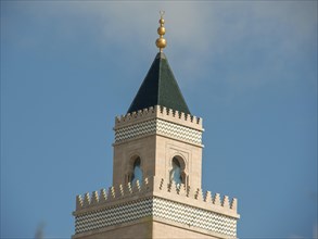 A tall minaret with a green spire and golden decorations rises into the sky, Tunis in Africa with