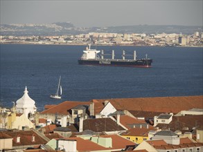 Panoramic view of the sea with a large ship and city buildings in the background, Lisbon, Portugal,