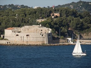 A historic fortress on the coast with a sailing boat and surrounding woods, la seyne sur mer,