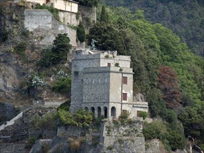 Historic stone building on an overgrown cliff, nestled in a lush green landscape, Bari, Italy,