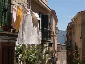 Colourful washing on linen between narrow houses, decorated with shutters and plants in the