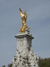 Golden angel statue rises on a marble pedestal, blue sky in the background, London, England, Great