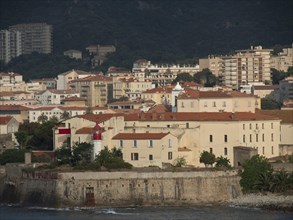 View of a historic fortress and old town with harbour and surrounding mountains on a sunny day,