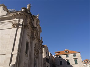 Magnificent ecclesiastical architecture with bright facades and statues against a deep blue sky,