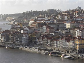 Panoramic view of a city along a river with boats and houses with red roofs, spring in the old town