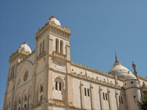 Large historic building with domes and decorations under a clear blue sky, Tunis in Africa with
