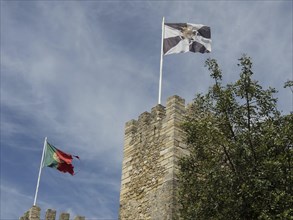 Two flags flying over a fortress wall under a cloudy sky, Lisbon, Portugal, Europe